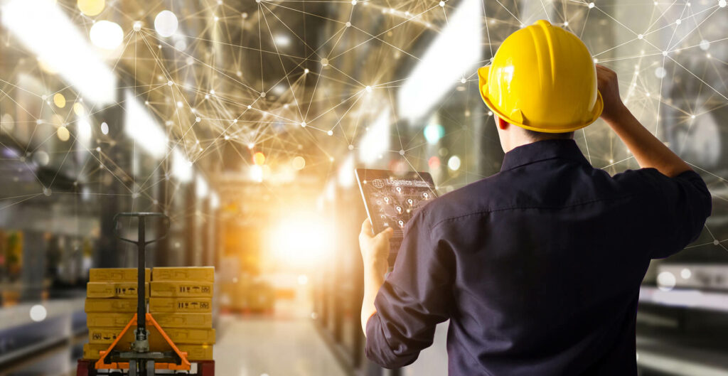 Lagerarbeiter mit Schutzhelm nutzt ein Tablet im Logistiklager, digitale Vernetzung und moderne Lagerlogistik im Hintergrund.